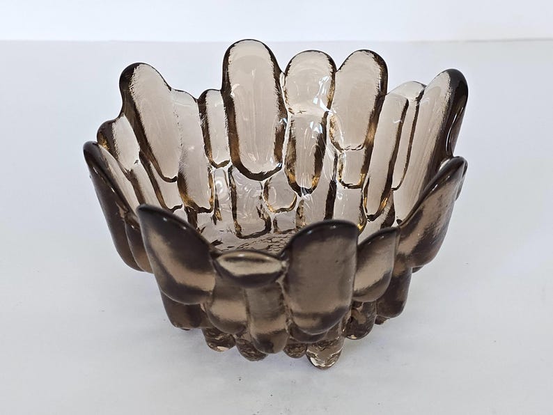 May include: A brown glass bowl with a unique, textured design. The bowl is shaped like a flower with many petals.