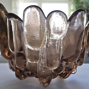 May include: A clear glass bowl with a unique, textured design. The bowl has a rounded shape and is made of thick glass. The glass has a slightly frosted appearance, giving it a vintage look.
