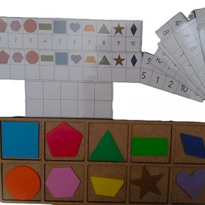 May include: A white ceramic mug with a black handle and the text "But First, Coffee" in a black, handwritten-style font. The mug is on a white surface.