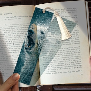 Pode incluir: Marcador de livros com uma ilustração de um urso polar com a boca aberta, sobre um fundo de texto. Possui um borla creme. Um acessório único para leitores.