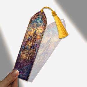 May include: A bookmark with a stained-glass castle design and a yellow tassel. The bookmark depicts a detailed castle illustration in blue, gold, and purple tones. The tassel is made of yellow thread.