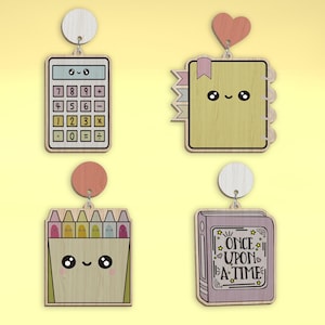 Puede incluir: Cuatro adornos de madera con un diseño de cara de dibujos animados lindo. Los adornos son una calculadora, un libro con el texto "ONCE UPON A TIME", una caja de crayones y un cuaderno con una cinta rosa.