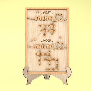 May include: Wooden sign with the words "First Mom" and "Now Mimi" in a scrabble tile design. The sign is on a small wooden stand.