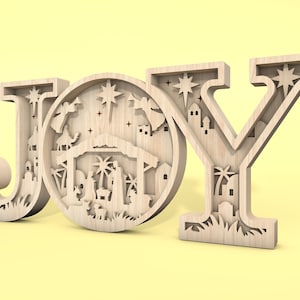 May include: Wooden JOY sign with a detailed nativity scene cutout in the centre of the O. The scene includes a stable, a star, palm trees, and figures of Mary, Joseph, and baby Jesus.