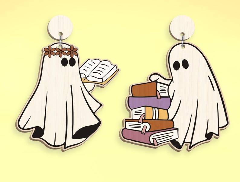 Op de afbeelding: Twee witte spookornamenten met zwarte ogen. E&eacute;n spook houdt een boek vast en draagt een bruine bloemenkrans. Het andere spook houdt een stapel kleurrijke boeken vast.