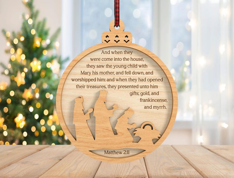 May include: Wooden Christmas ornament with a circular design. The ornament features a cutout nativity scene and text from Matthew 2:11. The text reads "And when they were come into the house...gifts; gold, and frankincense, and myrrh."