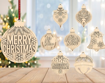 Op de afbeelding: Een verzameling houten kerstversieringen in diverse vormen, waaronder klokken en druppels. De ornamenten tonen gedetailleerde uitgesneden patronen, sneeuwvlokken en de zinnen "Merry Christmas" en "Let it Snow".