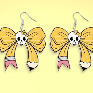 May include: A pair of yellow bow earrings with a skull in the center of each bow. The bows are designed to look like pencils with pink eraser details.
