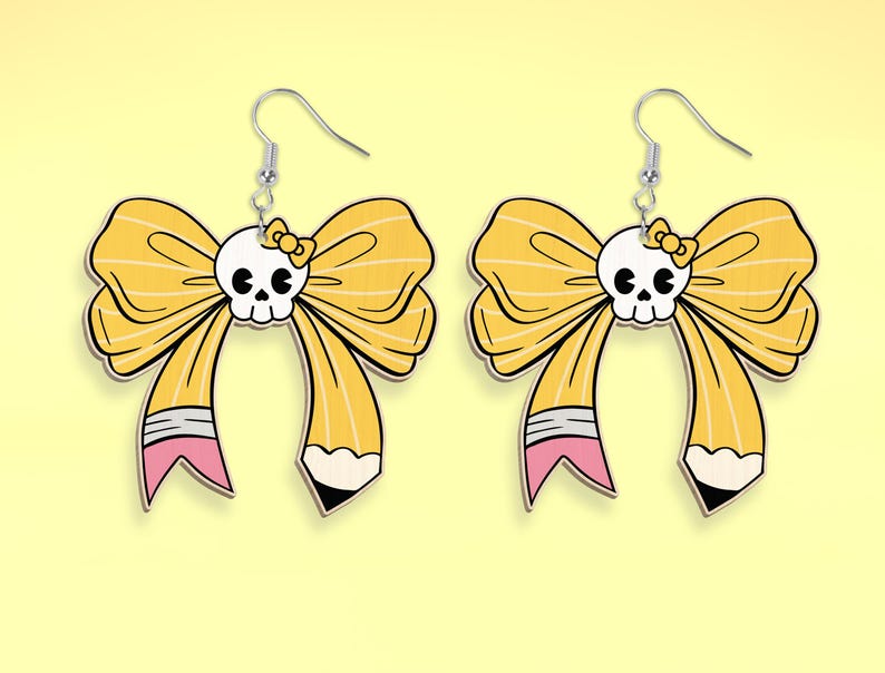 May include: A pair of yellow bow earrings with a skull in the center of each bow. The bows are designed to look like pencils with pink eraser details.