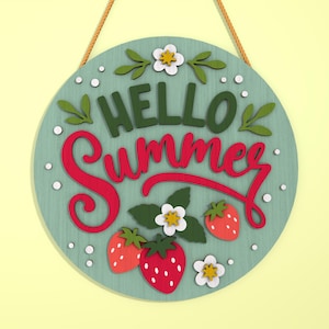 K&ouml;nnte beinhalten: Runder, hellblauer Holzschild mit den Worten "HELLO Summer" in gr&uuml;ner und roter Schrift. Das Schild ist mit Erdbeeren, wei&szlig;en Blumen und gr&uuml;nen Bl&auml;ttern verziert. Ein braunes Seil ist zum Aufh&auml;ngen befestigt.