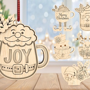 May include: Wooden Christmas ornaments in the shape of mugs, featuring festive designs like Santa, a snowman, and a reindeer. The ornaments are light brown with intricate cut-out details and include the words "Joy" and "Merry Christmas".