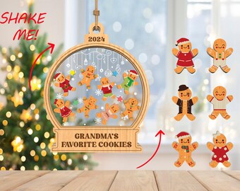 May include: A wooden Christmas ornament shaped like a snow globe with gingerbread people inside. The ornament has a red ribbon and the text "Grandma's Favorite Cookies" on the bottom. The ornament is surrounded by eight gingerbread people ornaments, each with a different design.