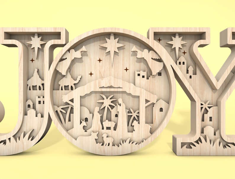 May include: Wooden JOY sign with a detailed nativity scene cutout in the centre of the O. The scene includes a manger, a star, palm trees, and figures of Mary, Joseph, and baby Jesus.