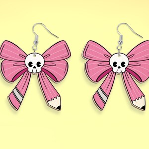 May include: A pair of pink bow earrings with a white skull charm in the center of each bow. The bows are shaped like pencils with a white eraser at the end.