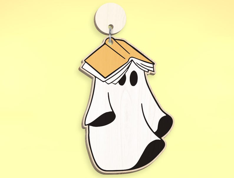 Op de afbeelding: Een witte geest met zwarte ogen draagt een geel boek op zijn hoofd. De geest is een houten ornament.