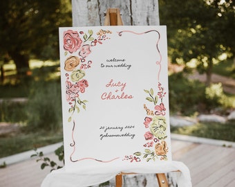Può includere: Un cartello di benvenuto per matrimoni bianco su un cavalletto, decorato con disegni floreali ad acquerello rosa, pesca e verdi. Il cartello recita "welcome to our wedding" e presenta i nomi "Lucy + Charles" e la data "20 gennaio 2024".