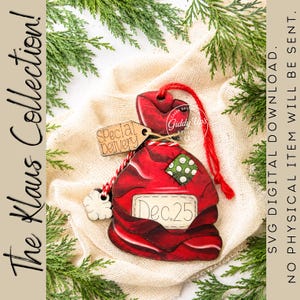 May include: A red wooden ornament shaped like a sack with a green polka-dot patch and a white label reading Dec. 25. A small wooden tag attached by twine reads Special Delivery. The ornament features a red string loop and a white cloud-shaped charm.