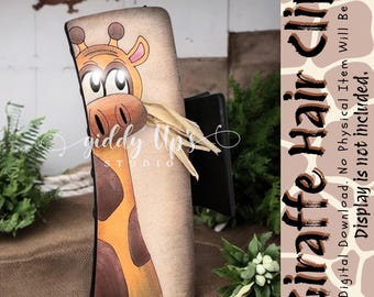 Könnte beinhalten: Ein Holz-Haarclip mit einem bemalten Giraffen-Design. Die Giraffe hat braune Flecken und einen langen Hals. Der Clip ist schwarz und hat eine braune Holzbasis. Der Text "Giraffe Hair Clip" ist in Schwarz auf einem braunen und weißen Giraffen-Druckhintergrund geschrieben.