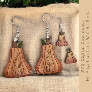 May include: Wooden pumpkin earrings with silver hooks and the text "It's Fall Y'all". The earrings are orange and brown with green leaf accents. Additional smaller pumpkin cutouts are also included.