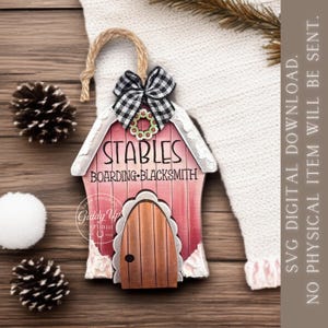 May include: A wooden ornament shaped like a barn with a pink facade, a brown arched door, and a black and white gingham bow. The text reads STABLES BOARDING BLACKSMITH. It features a small wreath detail and a jute twine loop for hanging.