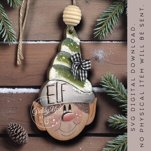 May include: Wooden elf-shaped Christmas ornament with a green and white hat, a black and white checkered bow, and the word "ELF" on the hat. The ornament has a smiling face and is hanging from a wooden bead.