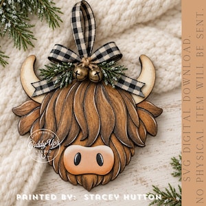 May include: A wooden Highland cow ornament featuring a brown layered design, a black and white buffalo check ribbon bow, two small brass bells, and green pine sprigs. The text Giddy Up's Studio is printed on the left, and SVG DIGITAL DOWNLOAD. NO PHYSICAL ITEM WILL BE SENT is on the right.
