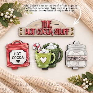 May include: A set of wooden decorative signs including a rectangular sign reading THE HOT COCOA STUFF, a red canister labeled HOT COCOA with a heart, two green mugs with marshmallows and a candy cane, and a jar labeled MARSHMALLOWS with white cubes.
