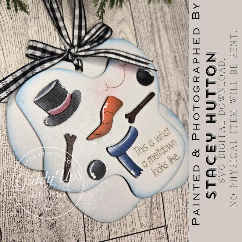 May include: A snowman-themed ornament with a black and white checkered ribbon. The ornament features a top hat, carrot nose, twig arms, and a blue scarf. Text on the ornament reads "This is what a meltdown looks like."