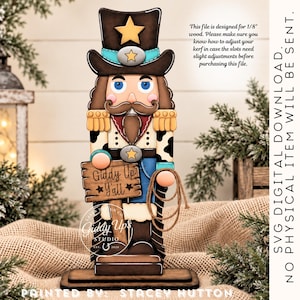 May include: A wooden nutcracker figure wearing a cowboy hat with a star, a turquoise band, and a cow-print jacket. It holds a sign reading Giddy Up Y'all and a rope lasso. Text notes this is a digital file for 1/8 inch wood.