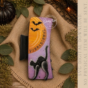 May include: A rectangular hair claw clip featuring a purple and orange gradient background with a black cat silhouette, two bats, and the text PURRANORMAL. The design includes a circular logo for Giddy Up's Studio and a black plastic hinge mechanism.