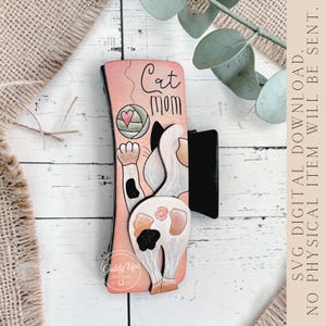 May include: A wooden cat-themed bookmark with a pink background. The design features a cat's rear end, a ball of yarn, and the words "Cat Mom." The bookmark has a black clip and the text "SVG DIGITAL DOWNLOAD. NO PHYSICAL ITEM WILL BE SENT."