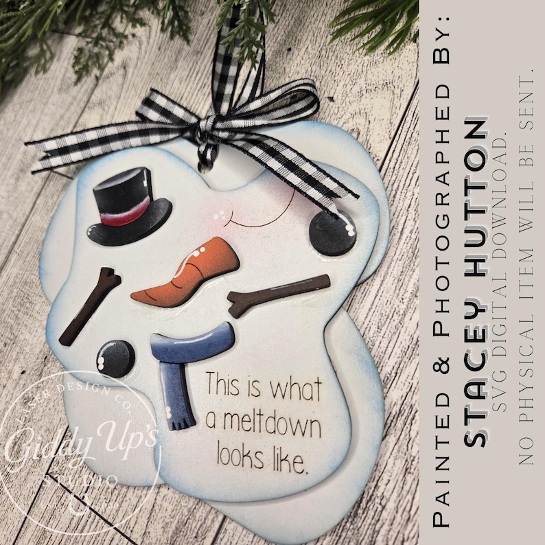 May include: A snowman-shaped ornament with a black and white checkered ribbon. The snowman has a black top hat, orange carrot nose, and a blue scarf. The text "This is what a meltdown looks like" is displayed.