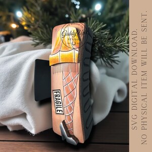 Puede incluir: Un dise&ntilde;o de madera cortado con l&aacute;ser que representa una pierna con medias de rejilla y un zapato de tac&oacute;n alto, con la palabra "FRAGILE". El dise&ntilde;o incluye el texto "Giddy Ups Studio" y "DESCARGA DIGITAL SVG. NO SE ENVIAR&Aacute; NING&Uacute;N ART&Iacute;CULO F&Iacute;SICO."