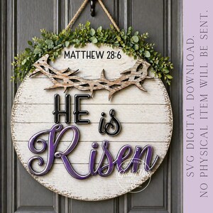 May include: A round wooden sign with the text "HE is Risen" in black and purple script. The sign includes a crown of thorns and is decorated with greenery. The text "MATTHEW 28:6" is at the top.