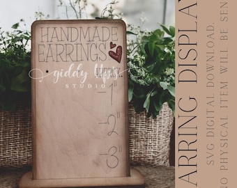 May include: A rectangular wooden earring display stand featuring the text HANDMADE EARRINGS, giddy studio, and markings for 1, 2, and 3 inches. The design includes two small red heart icons. The text EARRING DISPLAY SVG DIGITAL DOWNLOAD NO PHYSICAL ITEM WILL BE SENT is visible on the side.