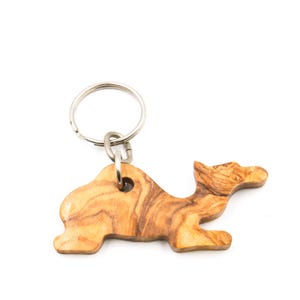 Op de afbeelding: Een houten kameel sleutelhanger met een zilveren sleutelring. De kameel is gesneden uit olijfhout en heeft een natuurlijke houtnerf.
