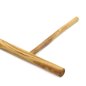 May include: A wooden crepe spreader with a long handle. The spreader is made of light brown wood with darker brown streaks.