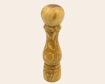 May include: A tall pepper mill crafted from light brown olive wood with a smooth, polished finish. The mill features a rounded top knob, a curved central body, and a cylindrical base, all displaying the natural, swirling grain patterns of the wood.