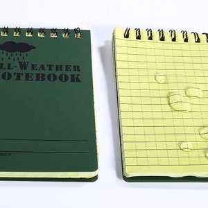 K&ouml;nnte beinhalten: Ein gr&uuml;nes Allwetter-Notizbuch mit einem schwarzen Wolken- und Regentropfen-Motiv. Das Notizbuch hat ein gelines Innenleben und ist wasserabweisend. Der Umschlag tr&auml;gt den Text "ALL-WEATHER NOTEBOOK" und Platz f&uuml;r einen Namen und eine ID-Nummer.