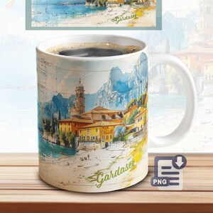 May include: White ceramic mug with a watercolor illustration of a town on a lake with mountains in the background. The text "Gardasee" is written on the mug.