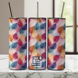 May include: Three stainless steel tumblers with a colourful leaf pattern. The tumblers are all the same size and have a straw sticking out of the top. The tumblers are sitting on a white surface. Digital PNG.