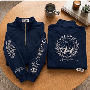 Könnte beinhalten: Marineblauer Sweatshirt-Pullover mit goldenem Reißverschluss. Auf der Vorderseite befindet sich eine Grafik einer Kapuzenfigur und der Text "Stay with the High Lord". Die Ärmel zeigen Mondphasen und den Text "hello feyre darling". Auf der Rückseite steht "VELARIS CITY OF STARLIGHT".