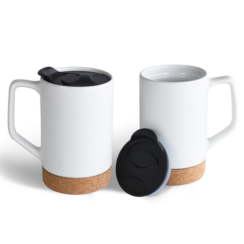 May include: Two white ceramic mugs with cork bottoms and black lids. One mug has a lid on it, and the other mug is empty.