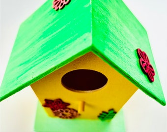 Linda casita para pájaros en colores primaverales con flores de madera. Amarillo brillante y verde neón.