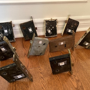 May include: Ten vintage door lock sets with numbered tags. The locks are made of metal and have a variety of finishes, including brass, silver, and black. Some of the locks have keyholes, while others have knobs.