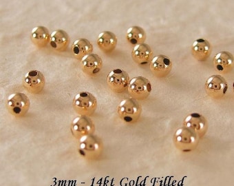 May include: A collection of 3mm gold-filled beads. The beads are round and have a hole in the center. 3mm - 14kt Gold Filled