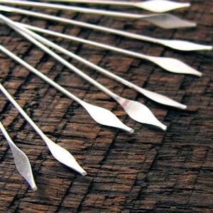 May include: A set of ten silver-toned, pointed, metal knitting needles with a diamond-shaped tip.