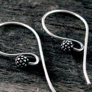 May include: A pair of silver hoop earrings with a textured ball charm on each hoop.