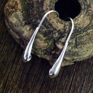 May include: A pair of silver teardrop-shaped earrings with a simple, minimalist design.