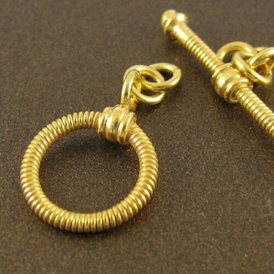 May include: Gold-toned metal toggle clasp with a coiled ring and a screw-on design. The clasp is a jewelry finding for necklaces, bracelets, or other jewelry projects.